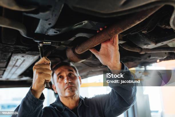 Mechanic Working Under A Lifted Car Stock Photo - Download Image Now - Car, Exhaust Pipe, Below