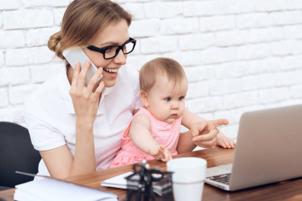 istock Young business lady try to work with cute baby. 984801902