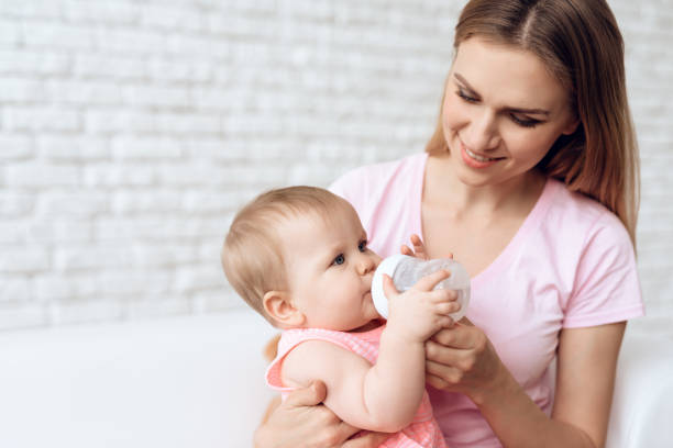 istock Smiling mother feeding baby milk bottle home. 984803542