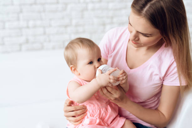 istock Young mother feeding baby milk bottle home. 984810004