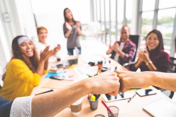 Business partners or coworkers fist bump in team meeting, multiethnic diverse group of happy colleagues clapping hands. Teamwork cooperation, team building, or success business project concept stock photo