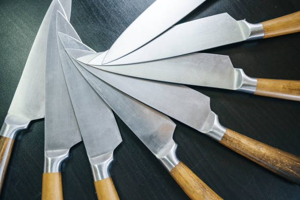istock Set of sharp knives with a wooden handle lie on a black table in the composition. 984811470