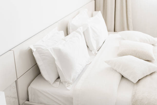 istock Modern double bedroom. Comfortable soft white pillows on a bed. Inside rooms of a apartment or hotel. 984818302