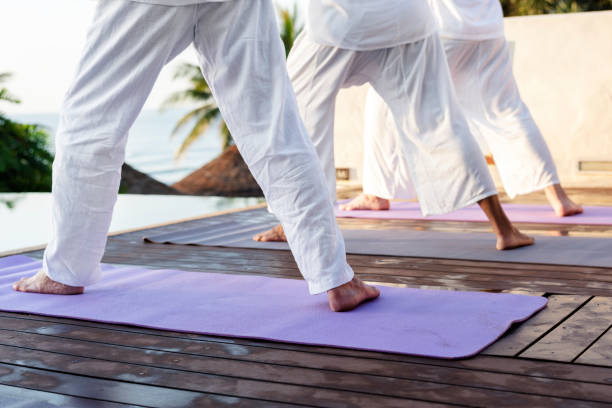 istock Group of seniors practicing yoga by the pool 984825364