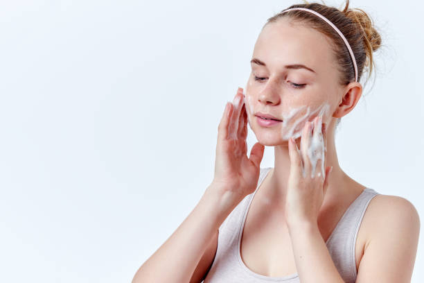 teenager skincare. beautiful teenage girl with freckles and blue eyes using foaming cleanser. face washing concept isolated on white background. - facial cleanser imagens e fotografias de stock