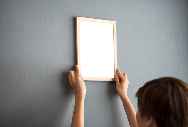 istock Hand Holding Blank white Photo Frame Hanging Wall for Design Mockup Template. 984847330