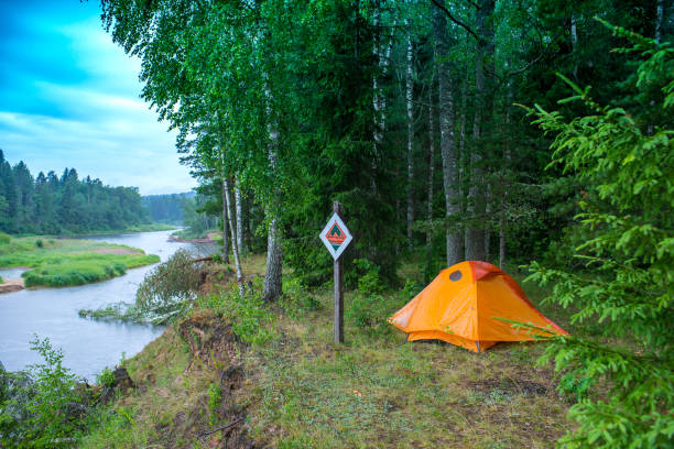 istock Orange tent on the river bank.  Forest tourism. 984871636