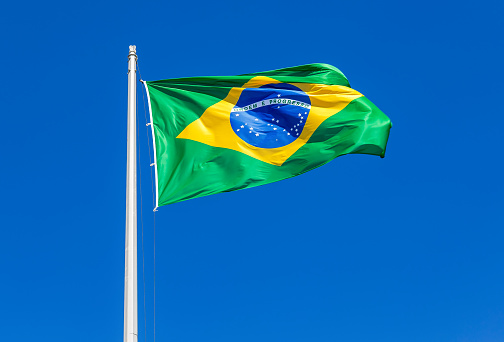 Flag of Brazil waving in the wind against the blue sky