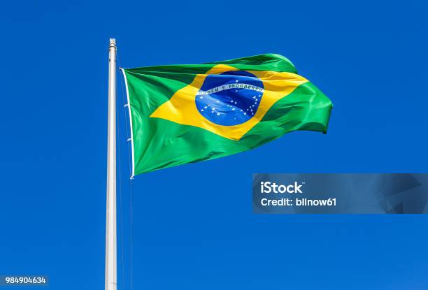 Flag Of Brazil Waving In The Wind Against The Sky Stock Photo - Download Image Now - Brazil, Flag, Banner - Sign