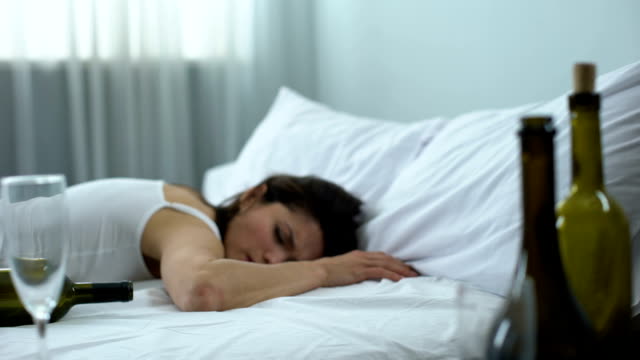 Drunk woman with headache waking up after night party, mess in room, hangover