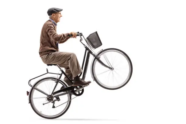 Mature man riding a bicycle and doing a wheelie isolated on white background