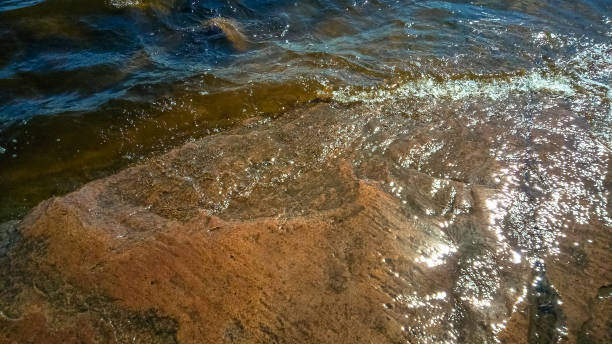 istock Granite beach with waves and dark water. Northern abstract natural background. 984966202