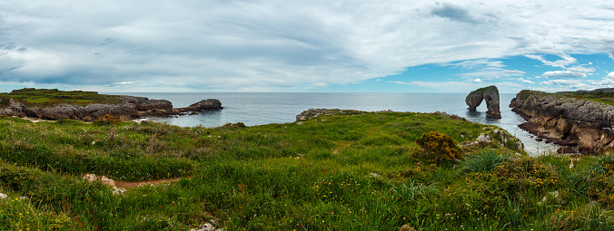 Cliffs and canyon in town of Llanes Villahormes, the islet known as Castro de las Gaviotas (Asturias, Spain). Two shots stitch panorama.
