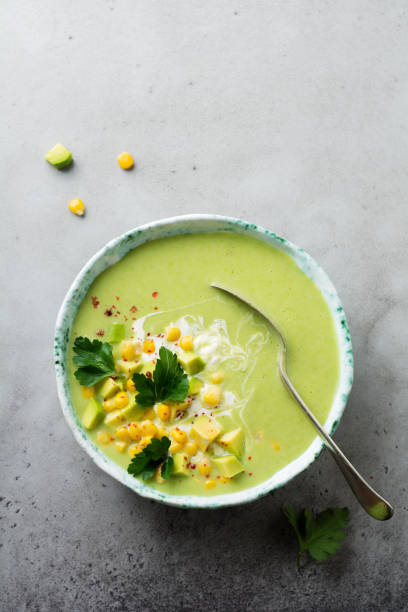 istock Homemade tender soup puree from avocado and corn with cream in rustic ceramic plate on gray concrete old background. Selective focus. Top view. Copy space. 984972060