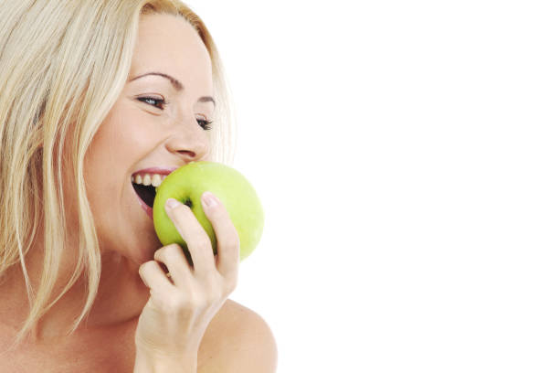 mujer rubia comer manzana verde sobre blanco - apple women green eating fotografías e imágenes de stock