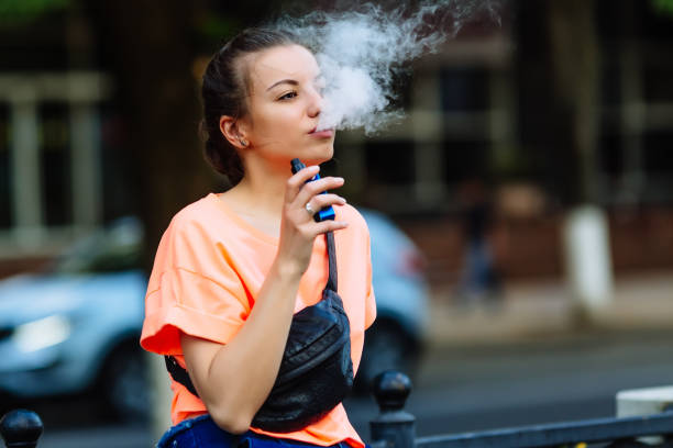 bastante joven hipster mujer vape ecig, dispositivo de vaping en la puesta de sol. tonos de la imagen - cigarrillo electrónico fotografías e imágenes de stock