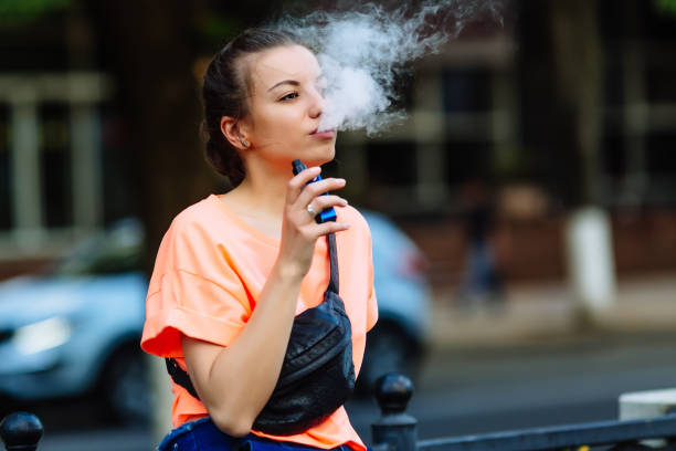 かなり若いヒップな女性アーク ecig、日没 vaping デバイス。トーンのイメージ - 電子タバコ ストックフォトと画像