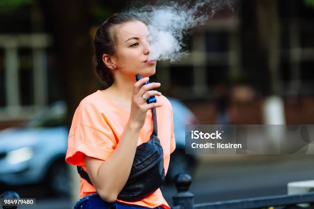 Foto de Hipster Muito Jovem Mulher Vape Ecig Dispositivo Vaping No Ocaso Imagem Enfraquecida e mais fotos de stock de Cigarro eletrônico