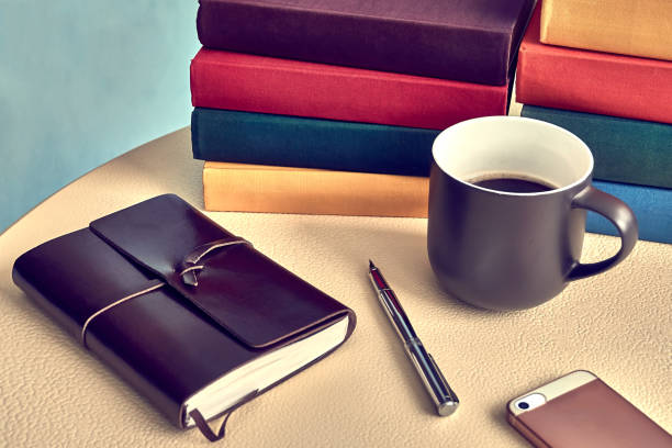 istock Desk with leather notebook, pen, smartphone, books and a cup of coffee. 984983412