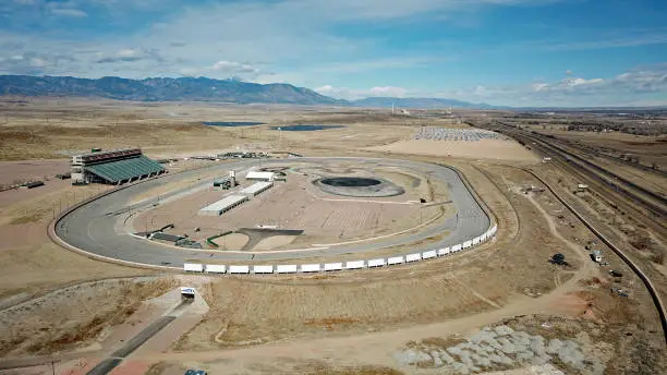 Aerial view of Pikes Peak racetrack in Fountain Colorado which used to host the Indy Racing League and Nascar Series. The Volkswagen recall parking lot, a solar farm, and the Rocky Mountains in the background.