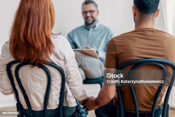 Giovane Bella Coppia Che Si Tiene Per Mano Durante Lincontro Con Il Consulente - Fotografie stock e altre immagini di Seduta di terapia