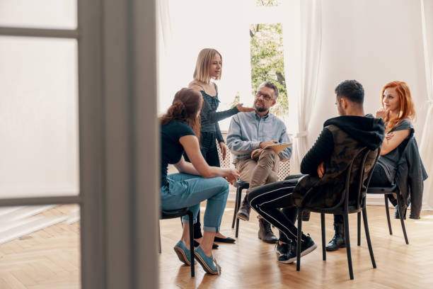 istock Young woman solving problems with friend during group therapy for teenagers 984989068