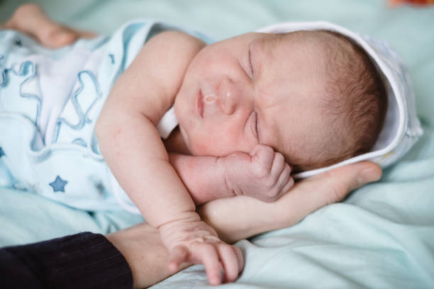 istock Newborn baby sleeping at home. Close up hands 984990700