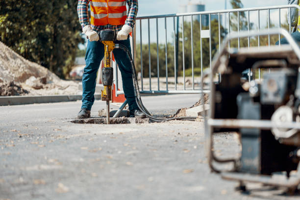 istock Craftsman in uniform with drill repairing asphalt during roadwork 985000494