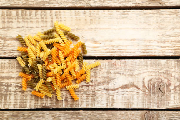 istock Spiral pasta on the brown wooden table 985002468