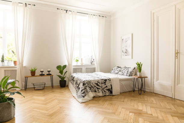 istock Patterned sheets on bed under poster in spacious bright bedroom interior with plants. Real photo 985006612