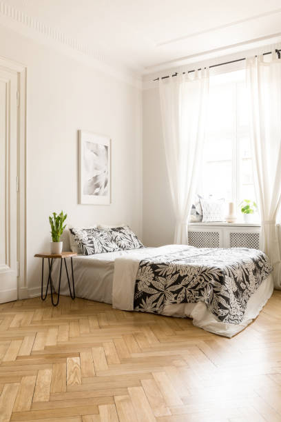 istock Poster above bed with patterned blanket in white hotel bedroom interior with window. Real photo 985006624