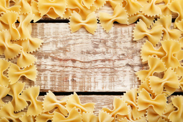 macarrão gravata na mesa de madeira marrom - bow tie pasta italian cuisine bow heap - fotografias e filmes do acervo