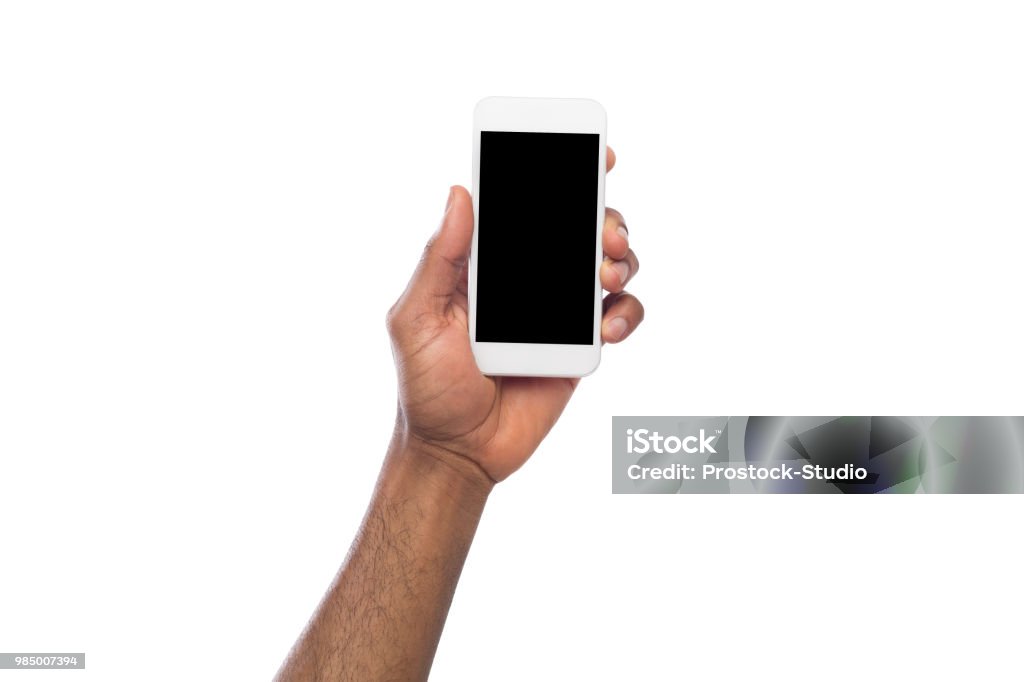 Hand holding mobile smartphone with blank screen African-american male hand holding mobile smartphone with blank screen, isolated on white background. Copy space for advertisement of mobile app, mockup Human Hand Stock Photo