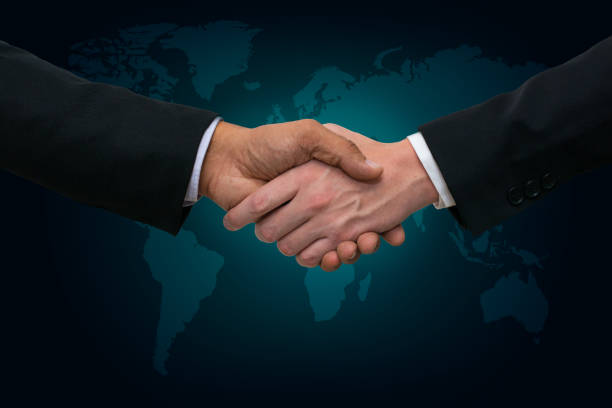 istock Business men shaking hands on a world map with blue green background 985012580