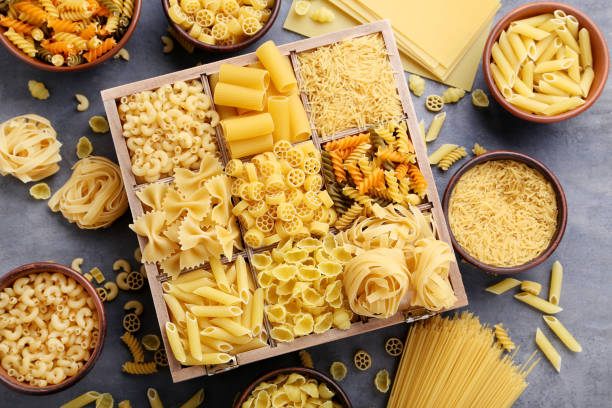 istock Different kinds of pasta on grey wooden table 985018694