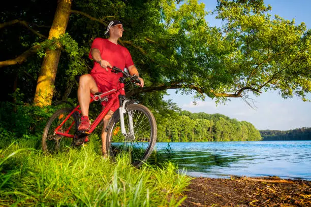 Vacations in Poland - Adult man rides a bike along the lake in Masuria land