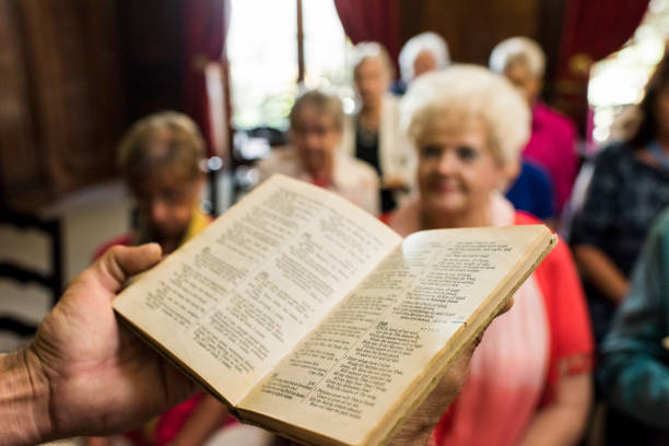 Detail of a church interior, a row of red hymn books on a church pew. Depicts religion and prayer