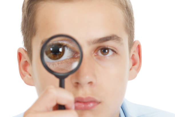 istock Funny Child with a magnifying glass at School. 985023864