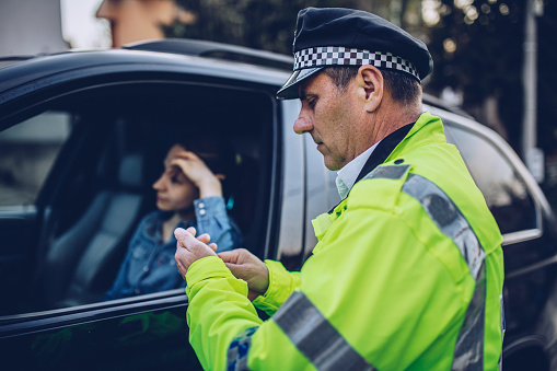 Young woman pulled over by police officer on the road.