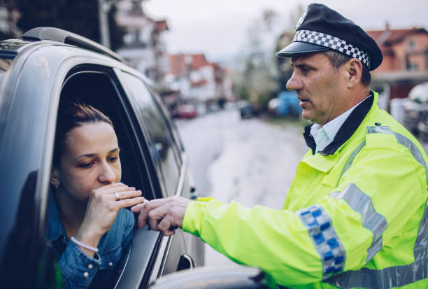 Police man giving woman breath test Woman pulled over by police officer and taking a breath test breathalyzer tests stock pictures, royalty-free photos & images