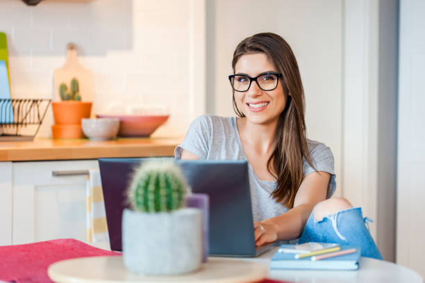 istock Female smiling at camera using laptop at home 985033662