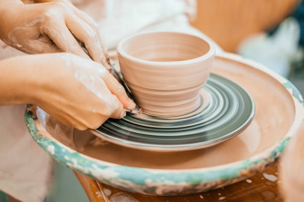 Modeling on a potter's wheel Women working on the potter's wheel. Hands sculpts a cup from clay pot. Workshop on modeling on the potter's wheel. ceramics stock pictures, royalty-free photos & images