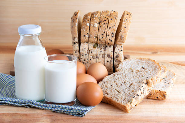istock Bottle of milk, eggs, and bread on the wooden table. with copy space for text. 985042390