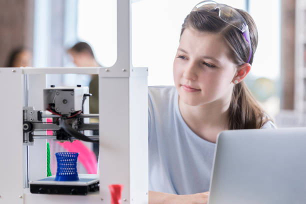 istock Confident teenage girl uses 3D printer 985047696