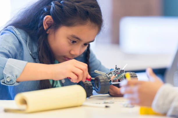 istock Cute elementary age girl building robotic vehicle 985047756