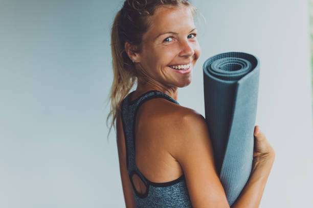 Healthy living- young woman with yoga mat Healthy living- young woman with yoga mat mat stock pictures, royalty-free photos & images