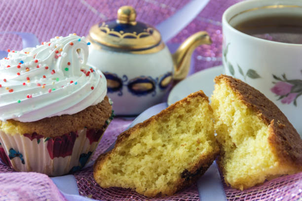 Split biscuit muffin and muffin, decorated with whipped protein cream, on the background cup of  tea  and teapot