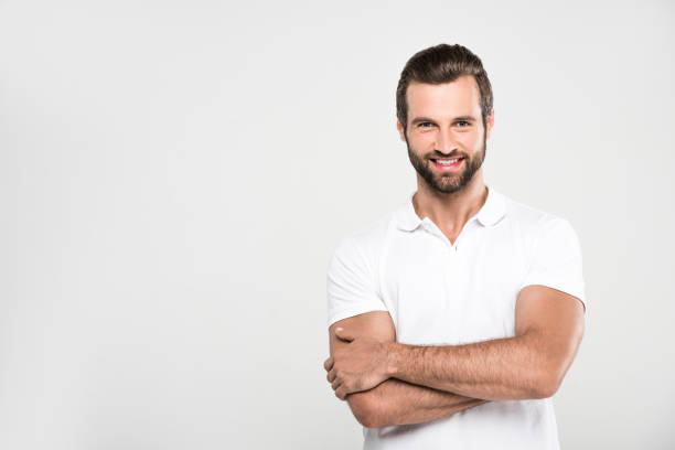 istock handsome smiling man posing in white with crossed arms, isolated on grey 985058636