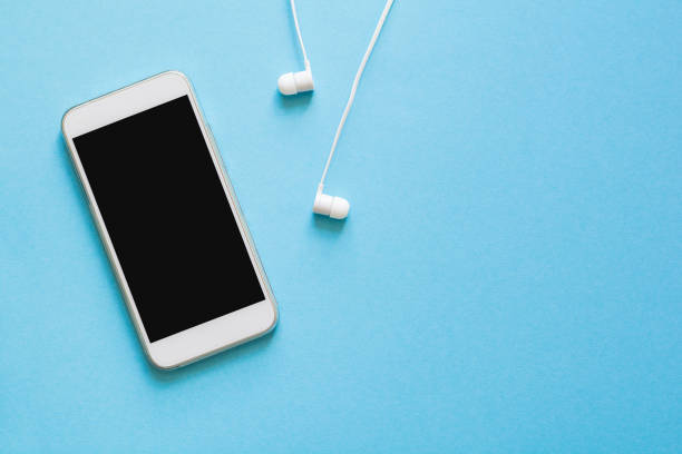 Top view mock-up smartphone and earphones on blue background. Flat lay. Space for copy