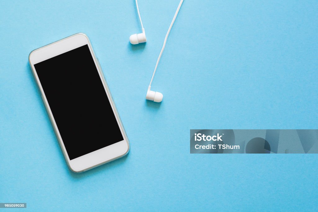 Top view mock-up smartphone and earphones on blue background. Flat lay. Space for copy Telephone Stock Photo